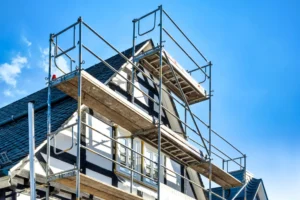 Scaffolding on house under clear blue sky.