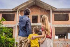 Family observing unfinished brick house construction.