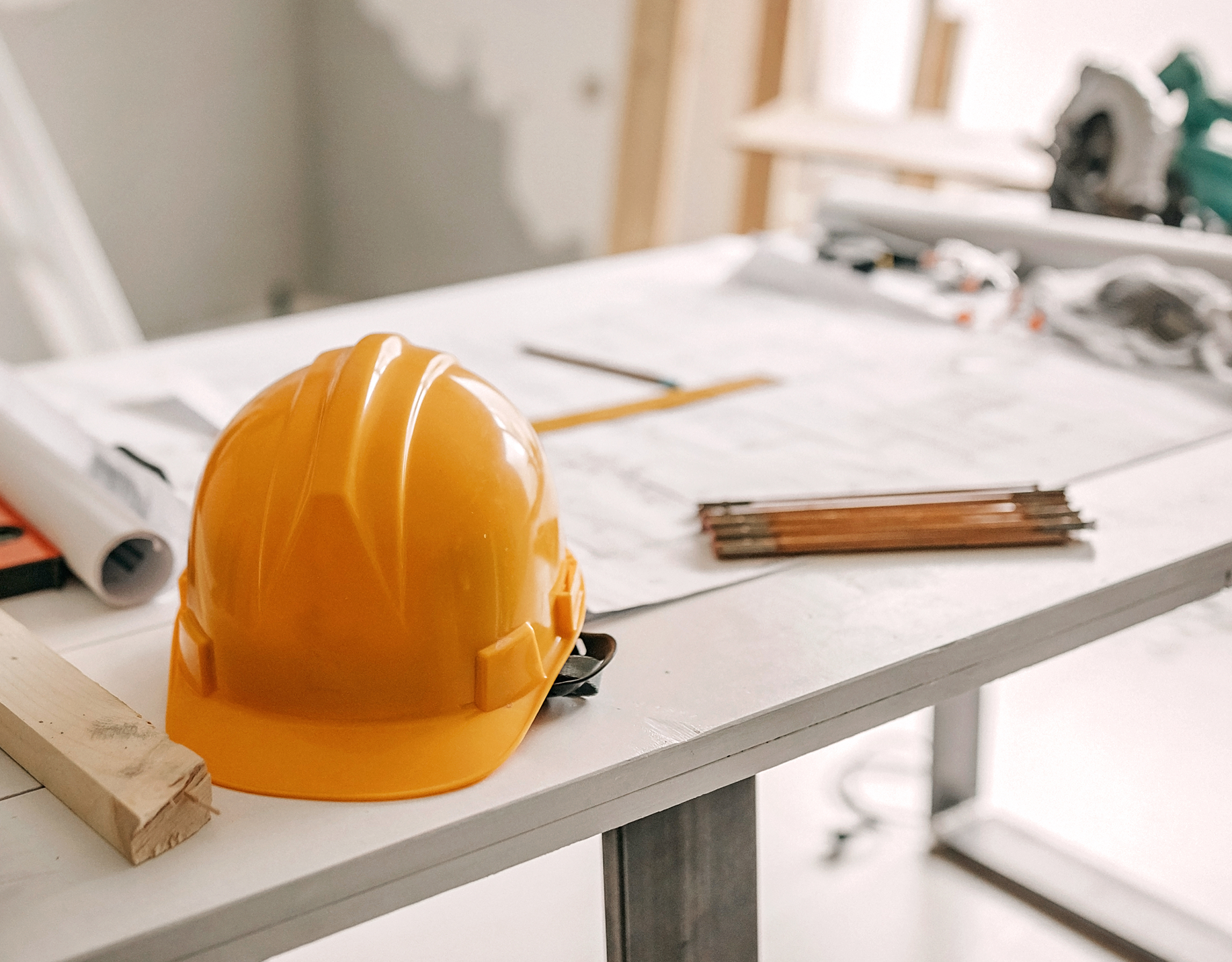 Yellow hard hat on construction desk.